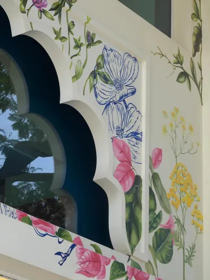 A close-up of the facade art, highlighting the intricate details of the flowers and the contrast between the painted sections and the line work. This piece is a portrait of Maharashtra's natural beauty.