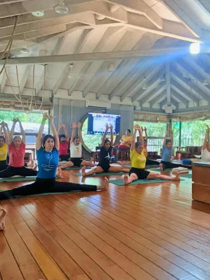 A vibrant class practices Upavistha Konasana (Wide Angle Seated Forward Bend). This pose requires focus and discipline to extend the spine and open the hips.