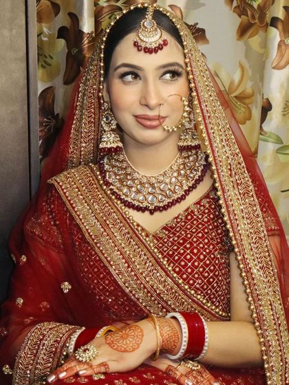 A classic bridal pose in a red lehenga, showcasing the heavy kundan jewellery and the complementing makeup.