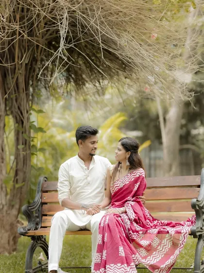 A serene portrait of the couple sitting on a park bench, dressed in traditional Maharashtrian attire. The natural setting complements the simplicity and elegance of their look.