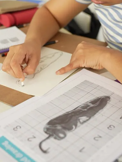 A close-up of a student using the grid method to ensure accurate proportions in their drawing, a fundamental skill we teach in the CFA course.