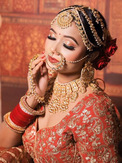 A close-up of the bride's face, showing the intricate details of the matha patti, nath, and choker from the golden jewellery set.