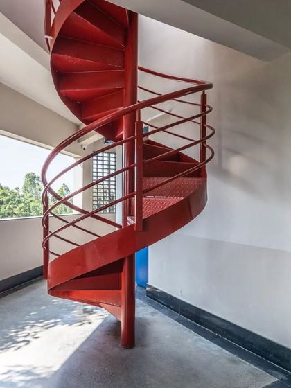 The sculptural red staircase at L'Atelier is a key feature, designed to be both a means of circulation and a piece of functional art.