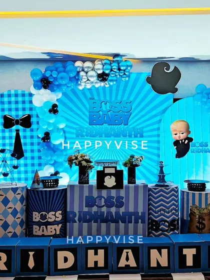 Here's a fun and stylish Boss Baby theme for Ridhanth's birthday. The decor features a bold blue and black color scheme, custom backdrops, and props like money bags and film cameras to capture the playful spirit of the movie.