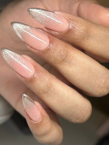A glamorous twist on the French manicure. This design features a sheer nude base with a sparkling silver cat-eye effect on the tips of these long, stiletto-shaped nails.