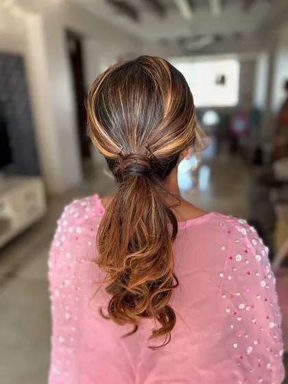 A modern and sleek ponytail with a hair-wrapped base. This style is perfect for highlighting the client's beautiful highlighted hair.