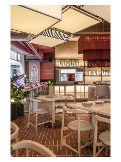 This perspective shows the harmony between different lighting sources, from the large patterned lanterns to the dramatic red tassel chandelier and the soft glow of the bar. Each light source is chosen to define a zone and contribute to the overall mood.