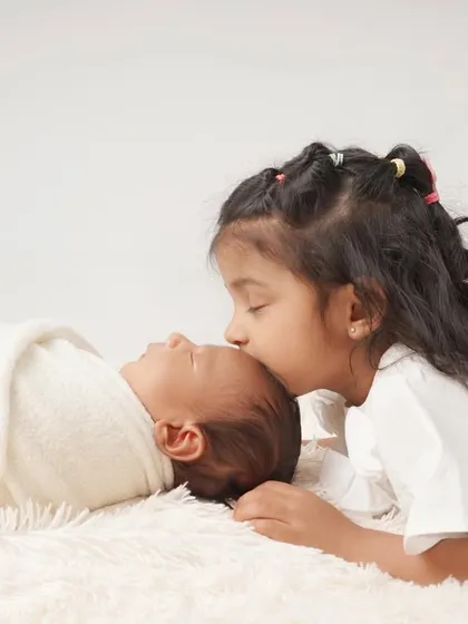 The first kiss from a big sister. Capturing the gentle, loving moments between siblings is one of the most rewarding parts of a newborn family session.