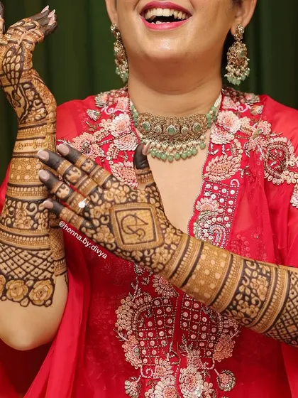 The back of the hands is just as important as the front. Here is a happy bride showing off her detailed back-hand mehendi, featuring a personalized initial monogram and beautiful floral and geometric patterns.