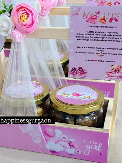 This image shows the details of a pink announcement basket, from the custom-printed base to the tulle-wrapped treat jars.