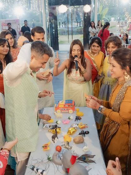 Guests fully engaged in a fun, hands-on game during the Godh Bharai celebration. Interactive elements are key to a lively and memorable event.