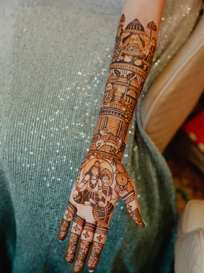 A detailed view of the arm featuring the Shiva-Parvati portrait, a beautiful and divine element in a bridal mehendi.