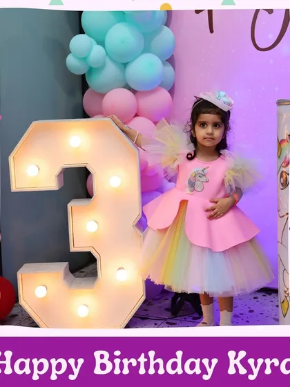 Birthday girl Kyra celebrating turning three in her unicorn-themed wonderland, complete with a light-up number and pastel decorations.