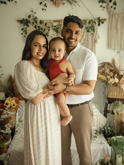 A picture-perfect family of three. This lifestyle portrait captures the family's bright smiles and easy connection in our warm, boho-chic studio setting.