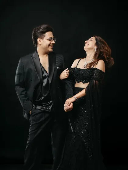 A candid moment of laughter between the couple during their studio shoot. Set against a dramatic black background, their shared joy and elegant black outfits create a sophisticated yet heartwarming pre-wedding portrait.