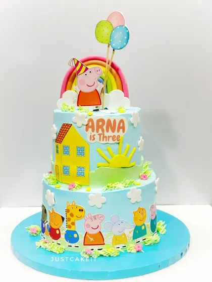 A bright and cheerful two-tiered Peppa Pig cake. This design is fondant-free, using colorful buttercream and edible printed toppers to create a happy scene with Peppa and her friends.