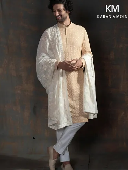 Elegance often lies in simplicity. This ivory kurta set is a study in quiet luxury, featuring subtle, hand-embroidered details that reveal themselves up close. Paired with an intricately worked stole, it’s an ideal ensemble for festive gatherings where refined style is key.