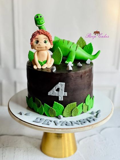 A prehistoric adventure featuring Arlo and Spot from The Good Dinosaur. This chocolate-covered cake is decorated with handcrafted fondant figures of the beloved characters, perfect for a young dinosaur fan.