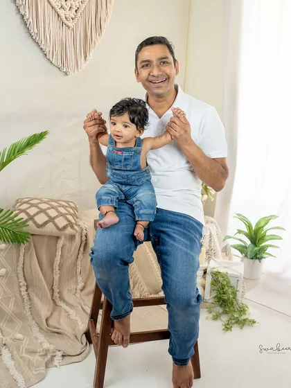 A proud father holds his baby's hands. This simple pose beautifully captures the connection between a dad and his little one.