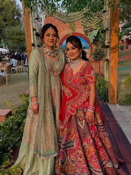 Posing together at a daytime wedding. Both clients are wearing looks I created, one more subtle and one more glam, showing the range of styles I offer.
