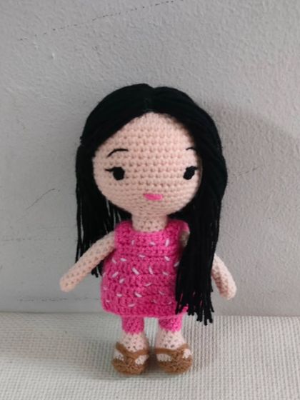 A simple and beautiful doll in a pink dress. Her long black hair is made from soft yarn.