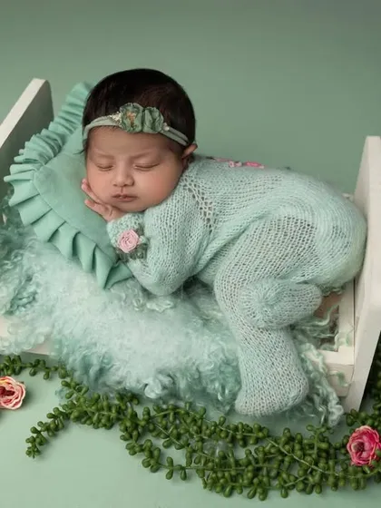 This angle captures the serene profile of the sleeping baby, highlighting the soft textures of the pillow and blanket in her tiny bed.