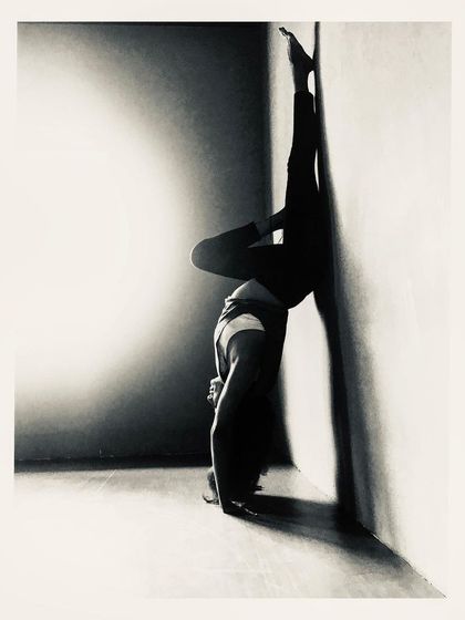 This artistic shot of a handstand variation against the wall plays with light and shadow. Inversions teach us to find stability and grace even when our world is turned upside down.