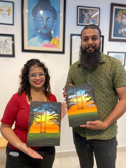A couple with their finished sunset paintings. It's a popular theme that allows for a lot of creativity with color blending.