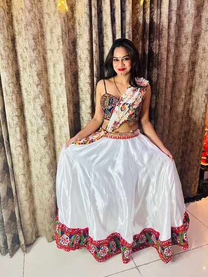 A model showing off the full white satin lehenga, a perfect canvas for the colorful mirror work blouse and dupatta.