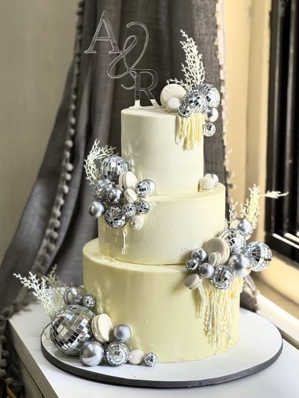 Glamour was the theme for this stunning three-tiered celebration cake. Adorned with sparkling silver disco balls and custom initials, it’s a showstopper designed to make any grand event unforgettable.