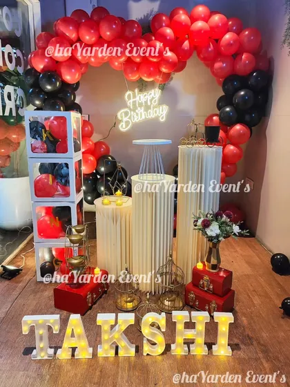 Another romantic heart-shaped balloon setup, this time in red and black. The marquee letters, pedestals, and neon sign make it a complete party corner.