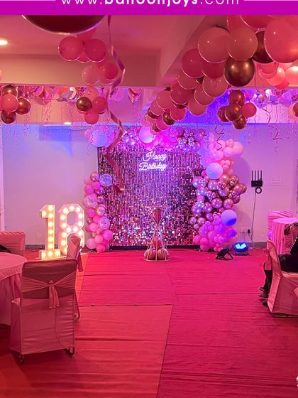 Stepping into adulthood with a splash of pink! This 18th birthday party is all about glamour, with a silver sequin wall, pink balloon arch, and large light-up marquee numbers.