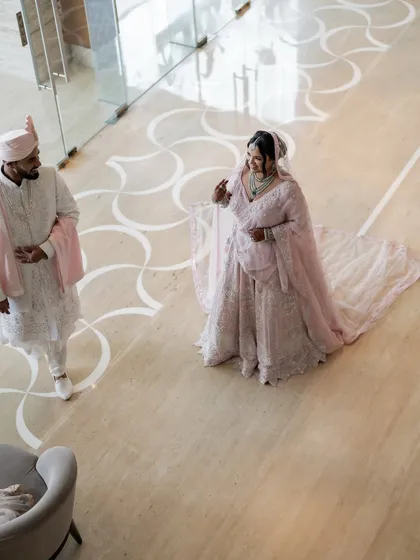 A high-angle shot of the couple in a spacious, modern lobby, showcasing the bride's long veil and the beautiful floor pattern.