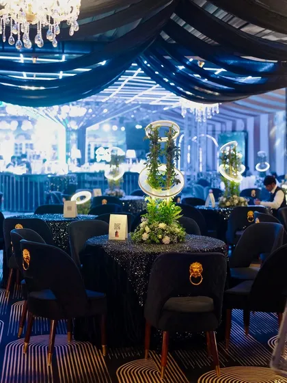 A wider view of the cocktail seating area, showing the dramatic black ceiling drapes and the cohesive, glamorous black and blue theme.