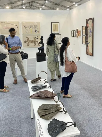 A group of visitors looking at the works of G. Ravinder Reddy and Pushpamala N.