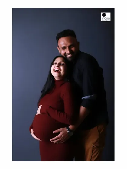 The pure joy and laughter of this couple shines through in this candid studio portrait, celebrating their journey to parenthood.