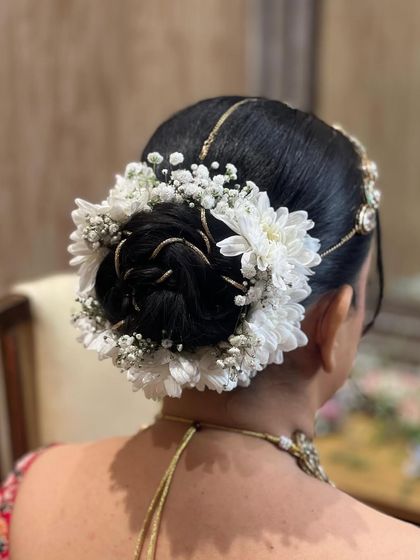An elegant and clean bridal bun decorated with baby's breath and white chrysanthemums, perfect for a sophisticated look.