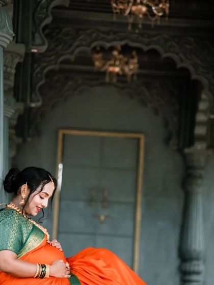 A serene moment captured as the expectant mother sits peacefully, framed by majestic pillars. This shot emphasizes the quiet joy and anticipation of motherhood.