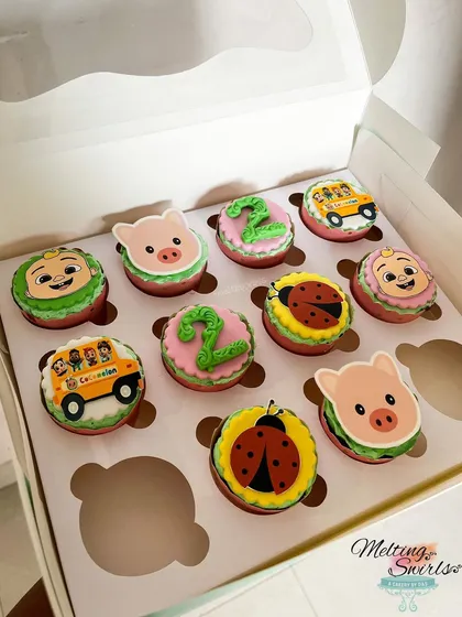 A box of our Cocomelon themed cupcakes, ready for a second birthday party. We included a variety of designs featuring JJ, the iconic school bus, cute pigs, ladybugs, and the number two.