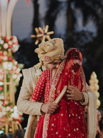 A tender moment as the groom embraces his bride from behind during the ceremony. This quiet, intimate gesture amidst the rituals is a beautiful expression of their love.