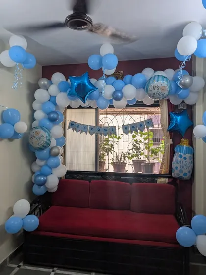 A closer view of the blue and white balloon arch. This setup includes star-shaped foil balloons, "It's a Boy" printed balloons, and hanging ribbons to add more detail and fun to the welcome home celebration.
