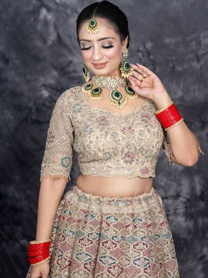 A full-length view of this gorgeous bridal lehenga. The makeup is designed to complement the outfit's intricate embroidery, with a focus on shimmering eyelids and a natural, glowing complexion.