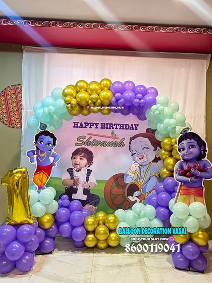 A charming Little Krishna theme for Shivansh's first birthday. This home setup includes a custom photo backdrop, character cutouts, and a balloon arch in purple, mint, and gold.