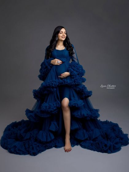 The rich texture and deep blue of this ruffled gown create a look of pure luxury. It’s a perfect choice for a glamorous and memorable maternity photoshoot.