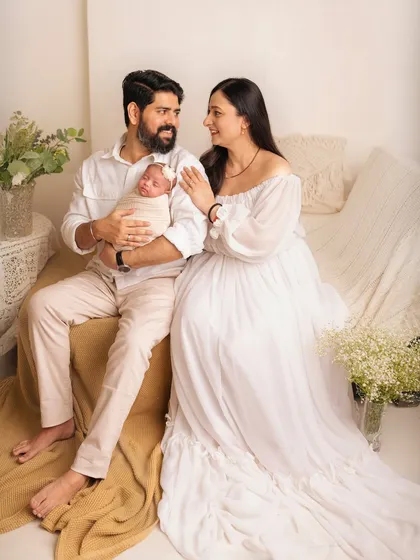 A full-length portrait of a new family relaxing together. The light and airy studio setup with neutral colors creates a calm and peaceful atmosphere.