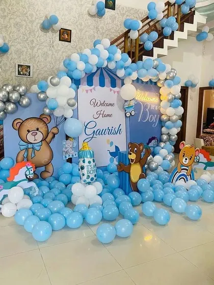 Another angle of the grand 'Welcome Home Gaurish' setup. This view shows the scale of the decoration, with balloons covering the floor and a large arch framing the custom backdrop and character cutouts.