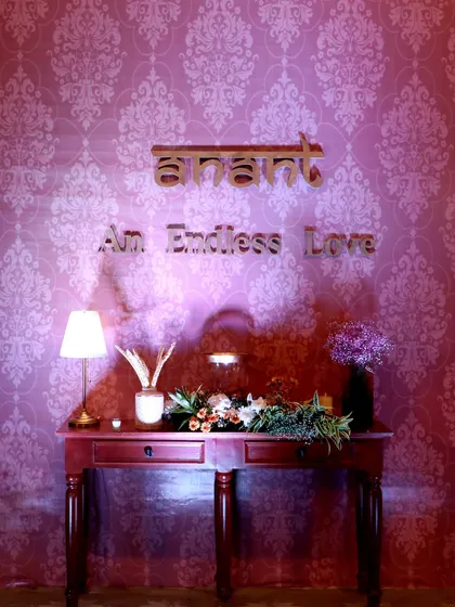 The theme name 'Anant, An Endless Love' is displayed as a decor feature, set against a damask-patterned wall, creating a perfect photo opportunity and reinforcing the wedding's core concept.