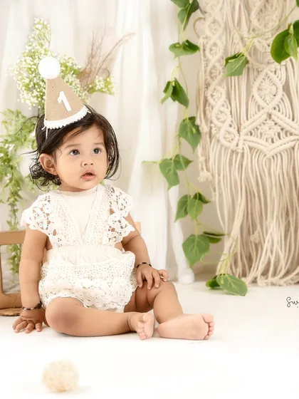 A quiet, observant moment during a busy first birthday shoot. The simple props and neutral tones keep the focus on her.