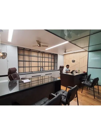 Another angle of the minimalist office cabin for Mr. Vishesh. The design includes a glass partition to maintain a sense of openness, while the wooden flooring and paneled walls add warmth and texture to the professional environment.
