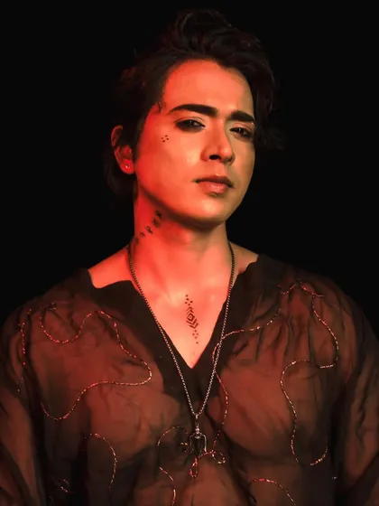 A dramatic shot of the male model under red lighting, showcasing the edgy, editorial style of the makeup.
